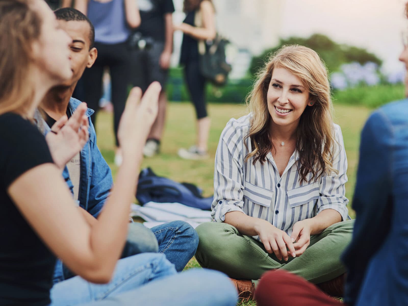 Flera personer sitter och pratar på en gräsmatta